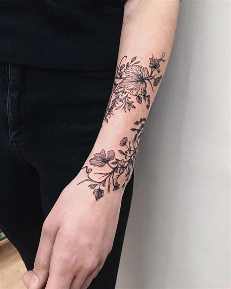 The clock is at the base of the design, with a rose on top of it which the angel wings design follows. . Flower wrist wrap tattoo